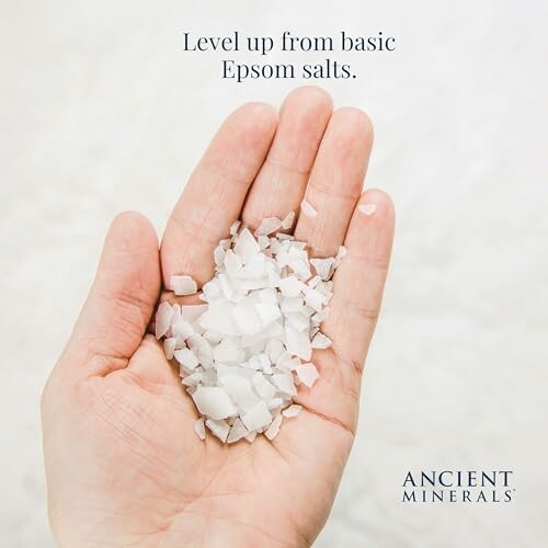 Hand holding Epsom salts with text 'Level up from basic Epsom salts' and 'Ancient Minerals' logo.