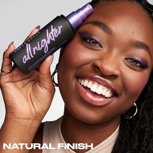 Smiling person holding Urban Decay All Nighter setting spray.