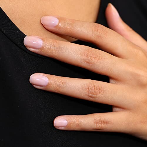 Close-up of a manicured hand resting on a black top.